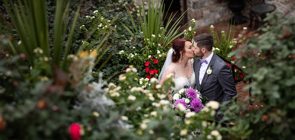 A bride and groom kissing with flowers all around them.