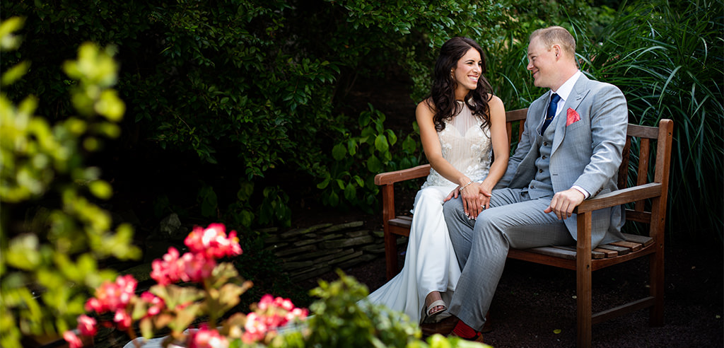 A bride and groom sitting on a bench