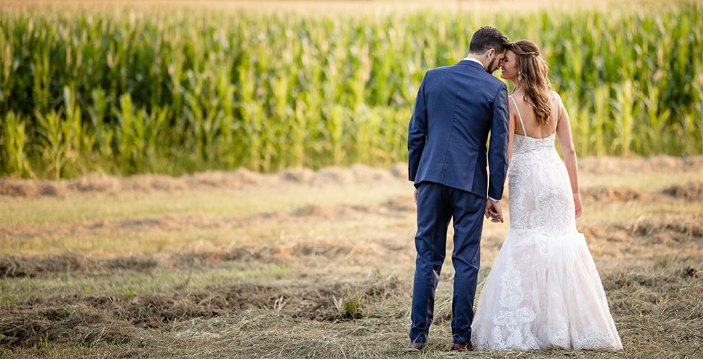 A bride and groom standing forehead to forehead in a field. This is for the article called how to pay for a wedding.