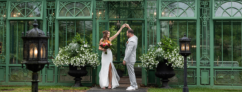 A bride and groom dancing outside a green building.