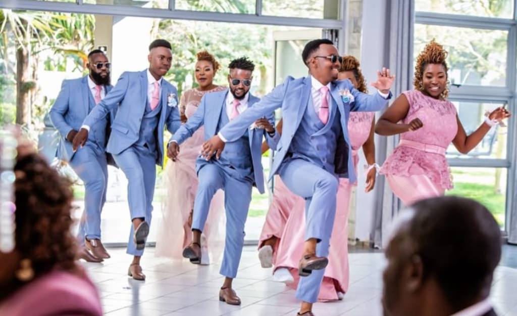 A wedding party dancing their way into the reception in one big group
