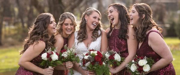 A bride and bridesmaids laughing together. This is the cover photo for the bridesmaid packing list article