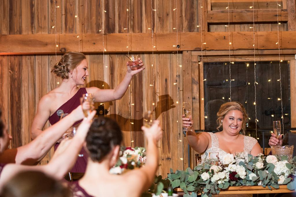A Maid of Honor ending her speech to the bride. They are both raising their glasses.