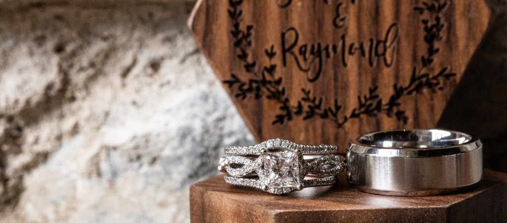 Two wedding bands sitting on an engraved ring box.