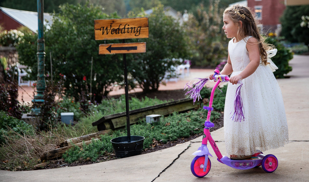 A flower girl entering the ceremony on a scooter