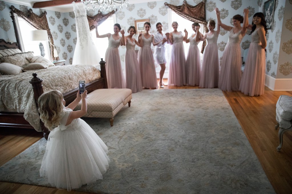 A flower girl taking photos of the bride and bridesmaids