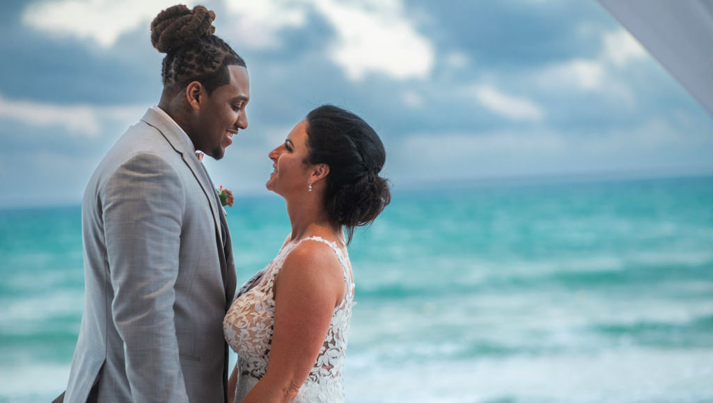 A bride and groom posing for the wedding photographer at the beach