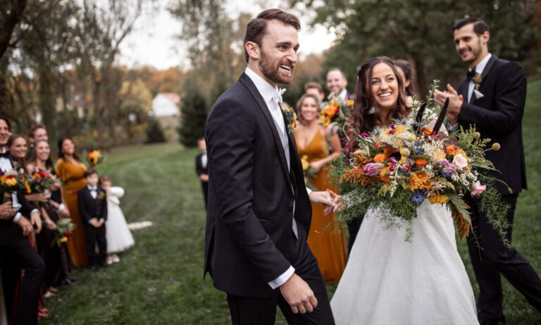 This is the cover photo for how to plan a wedding step by step. This shows a groom and bride smiling with the wedding party in the background