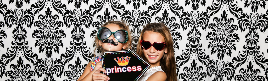 Two kids posing in a photo booth at a wedding