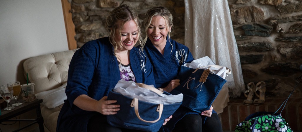 Two bridesmaids opening gifts from the bride