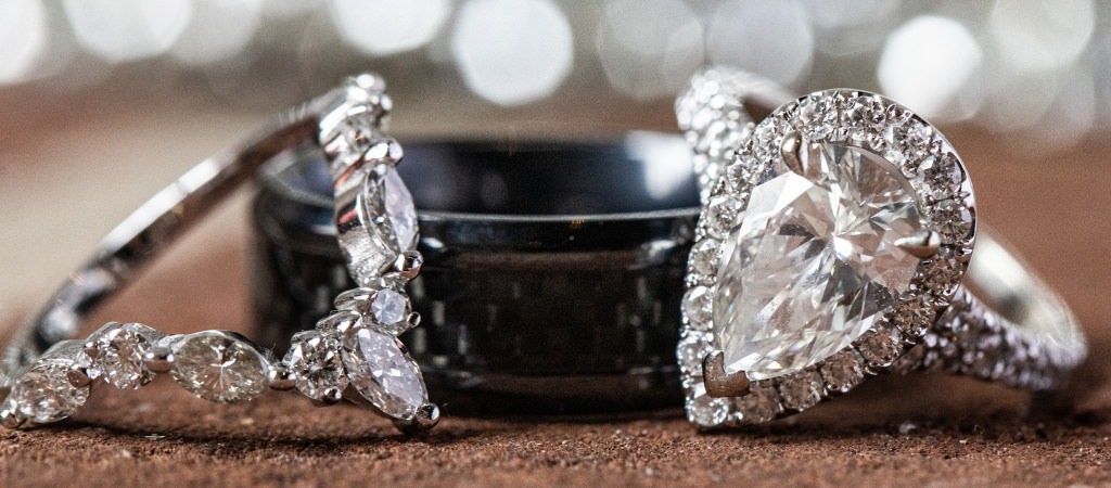 A man's wedding band and a woman's engagement ring and wedding band sitting side by side.