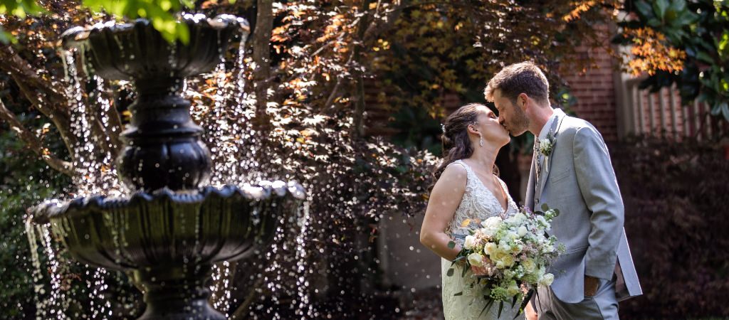 A bride and groom posing with a spring fountain after their wedding