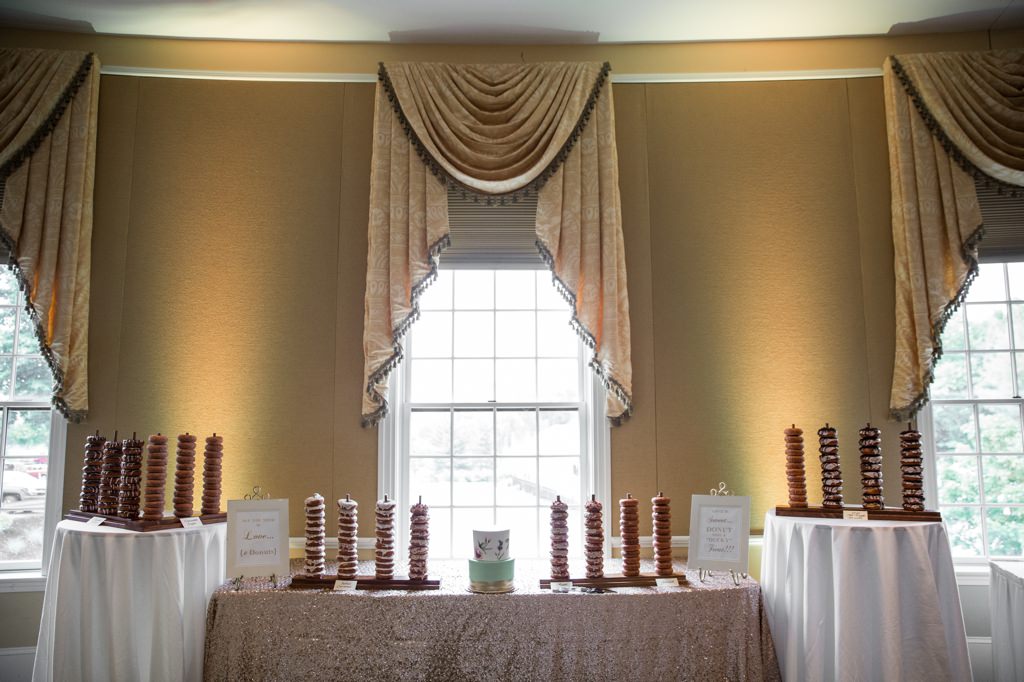 A wedding dessert table that features stand of doughnuts