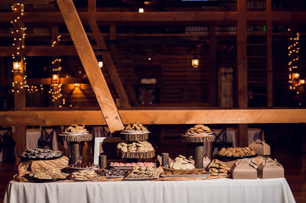 A cookie display on wooden rustic cake stands at a wedding. This is for the article called wedding dessert table ideas on a budget