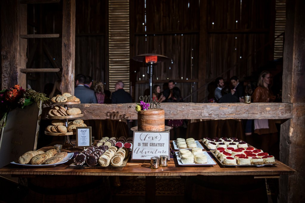 A wedding dessert table filled with cake cookies and whoopie pies