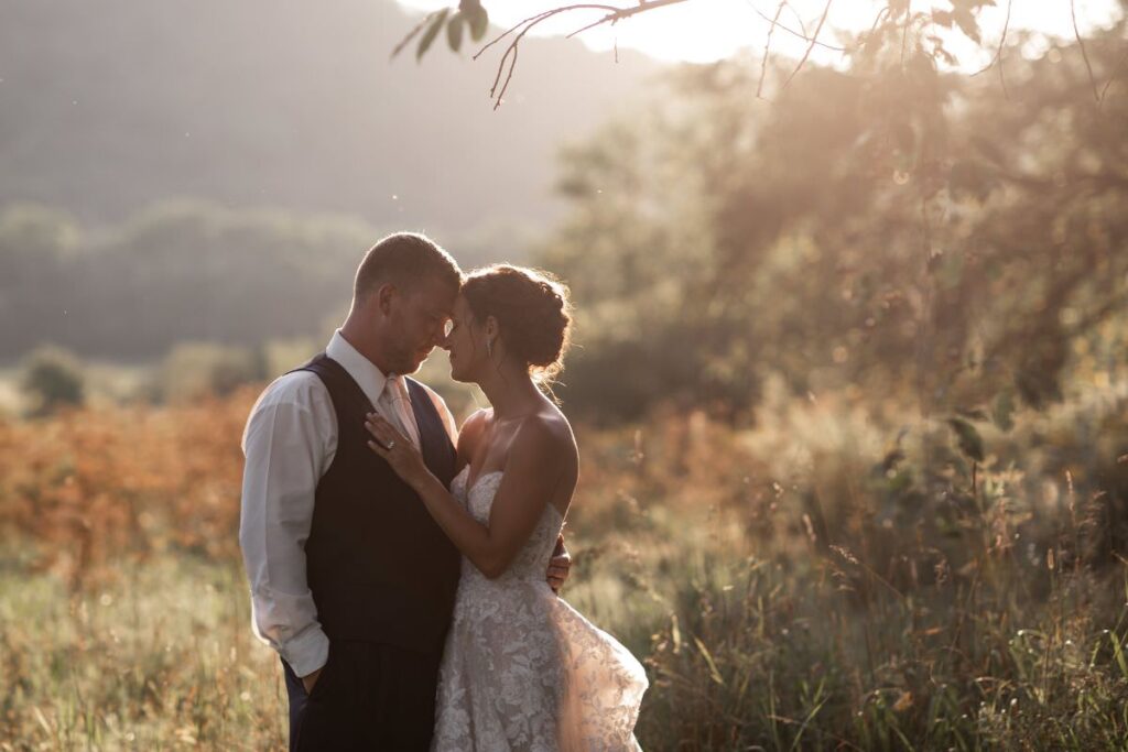 A bride and groom posing outdoors at sunset