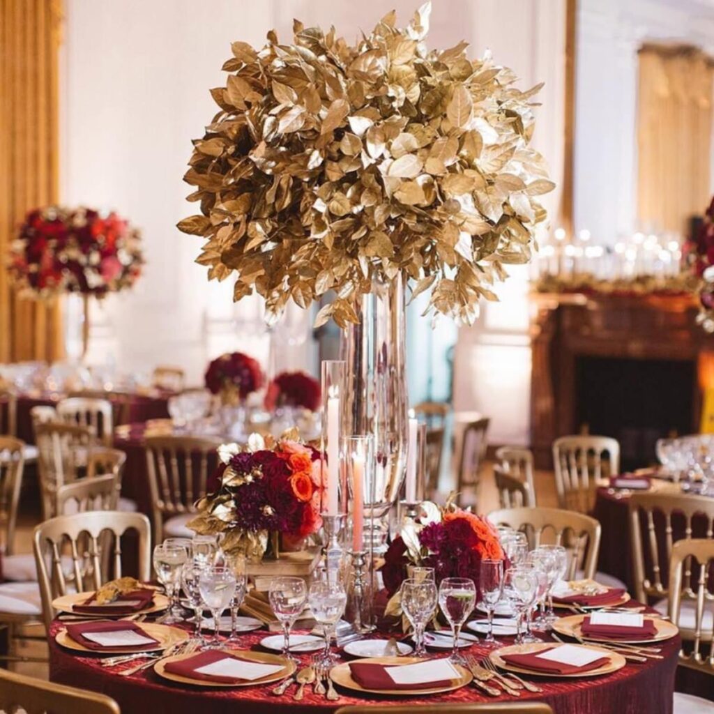 A Christmas wedding centerpiece with tall vases and gold flowers