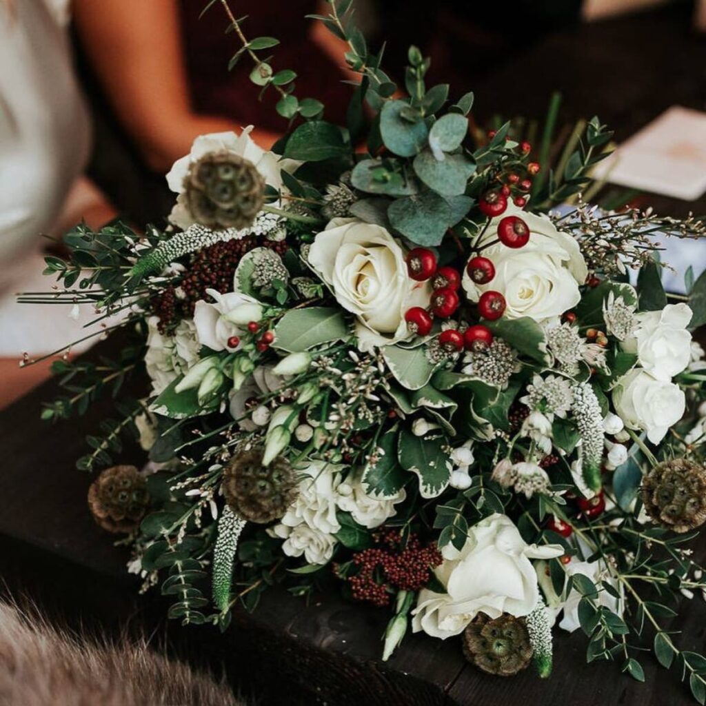 A Christmas wedding bouquet with red berries and white flowers. This is for the article called Christmas Wedding Flowers and Bouquets.