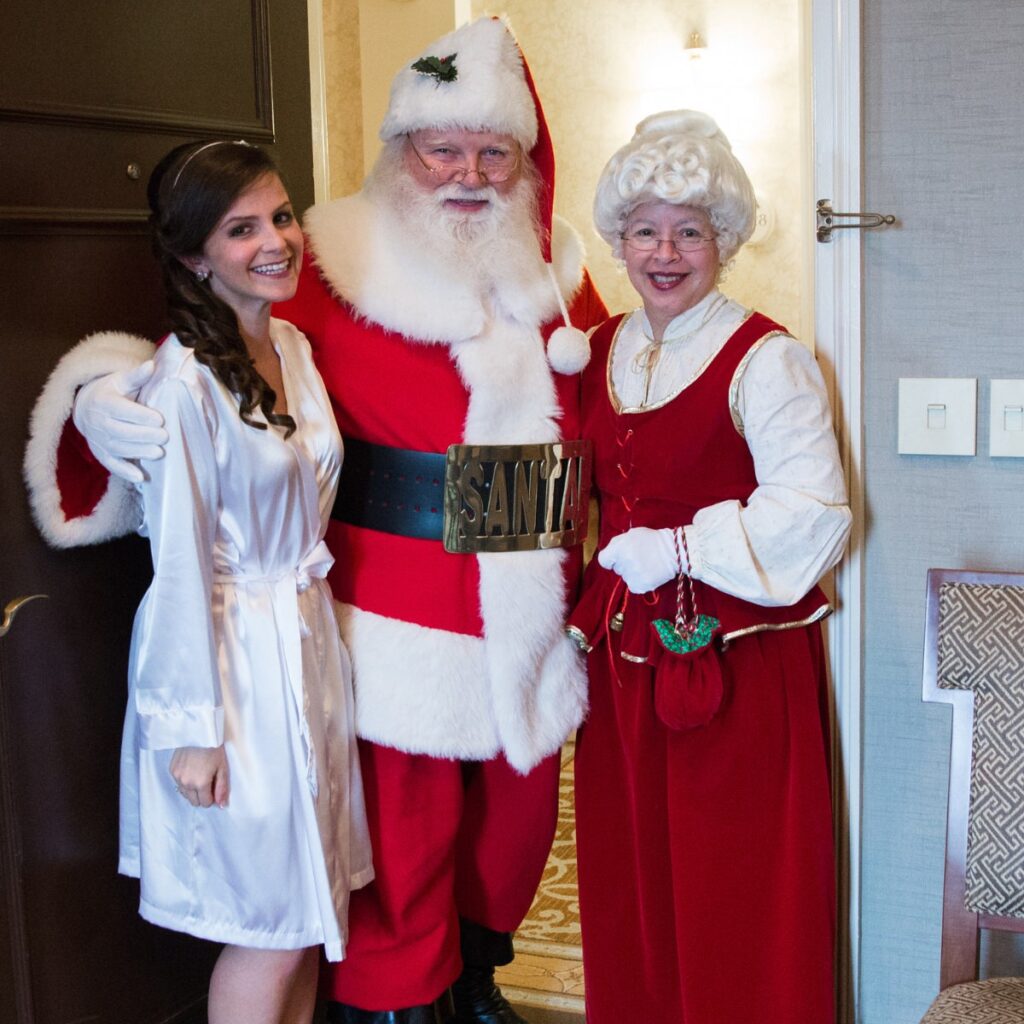 A bride posing with Santa Claus and Mrs. Clause at her wedding that had a Christmas theme