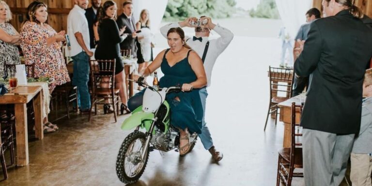 A photo of a bridesmaids and groomsmen riding into the reception on a dirt bike. This is the cover photo for the blog post called funny wedding party entrance ideas