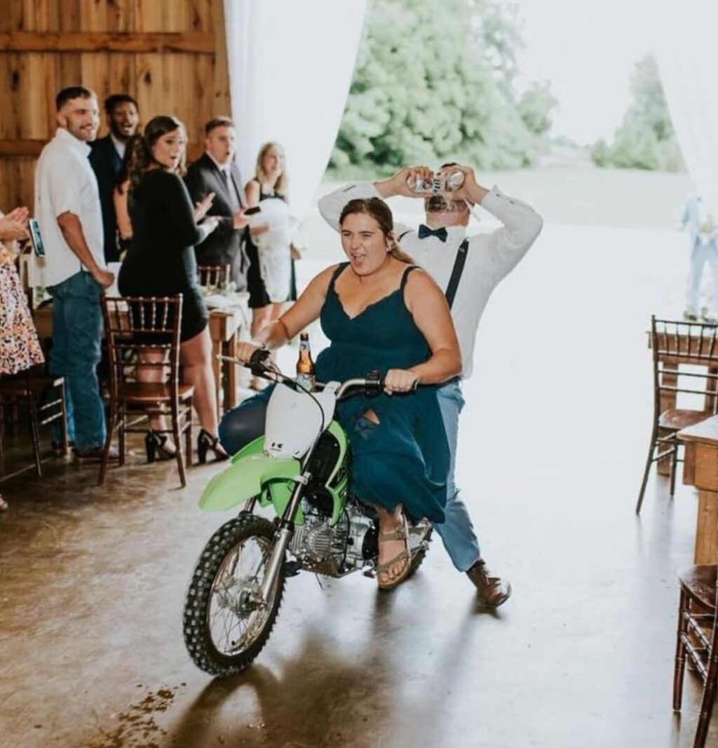 A Maid of Honor and Best Man riding into the wedding reception on a dirt bike