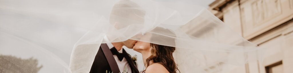 A bride and groom kissing. This is for the blog post called how to plan a wedding for 10000 or less