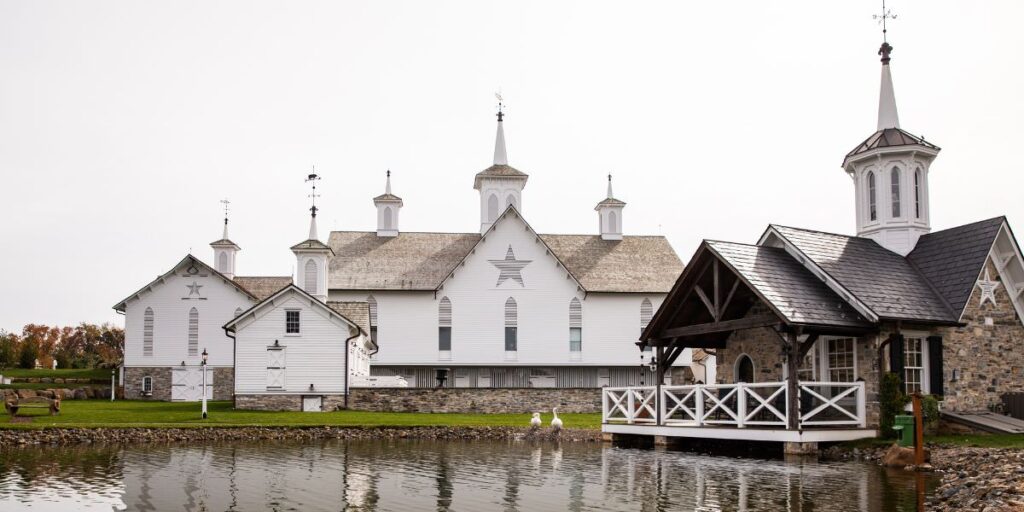 A beautiful white barn wedding venue with a pond in front