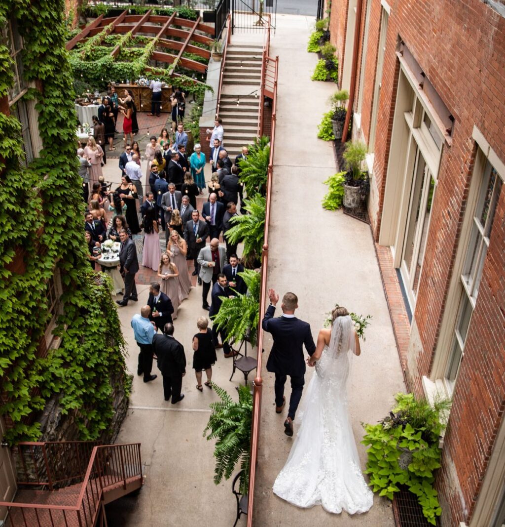 A couple walking and waving at their wedding guests