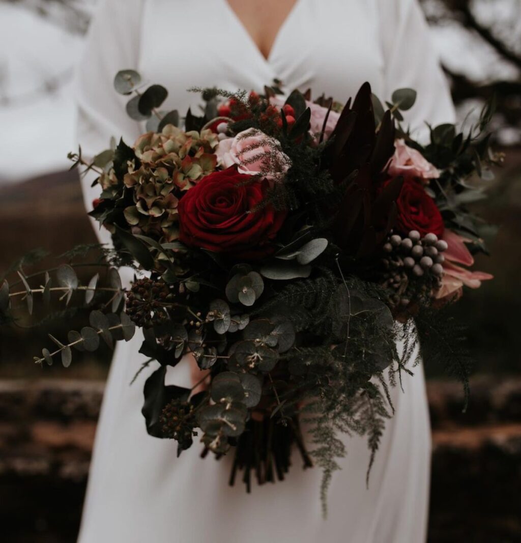 a dark and moody winter bridal bouquet with deep red flowers