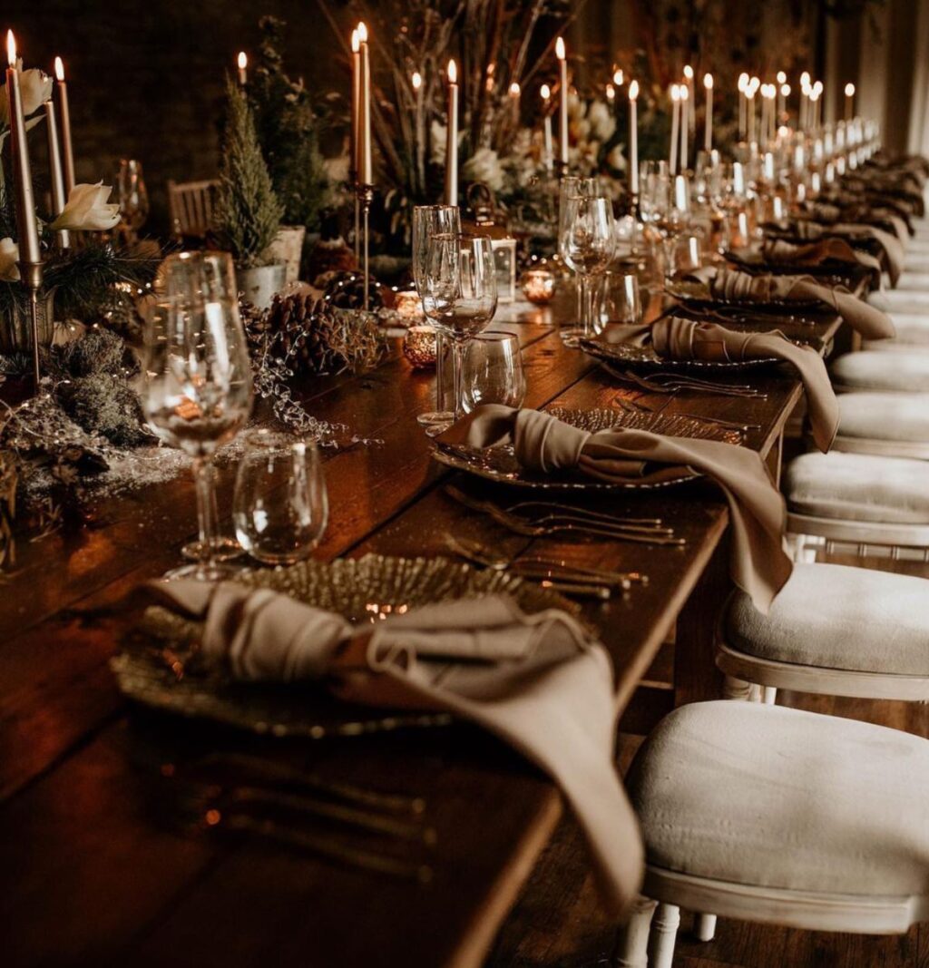 a moody winter wedding reception decorated table with candles and pinecones