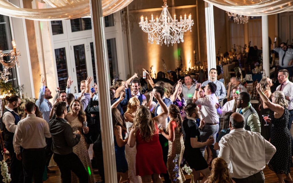 A group of guests dancing to music at a wedding reception