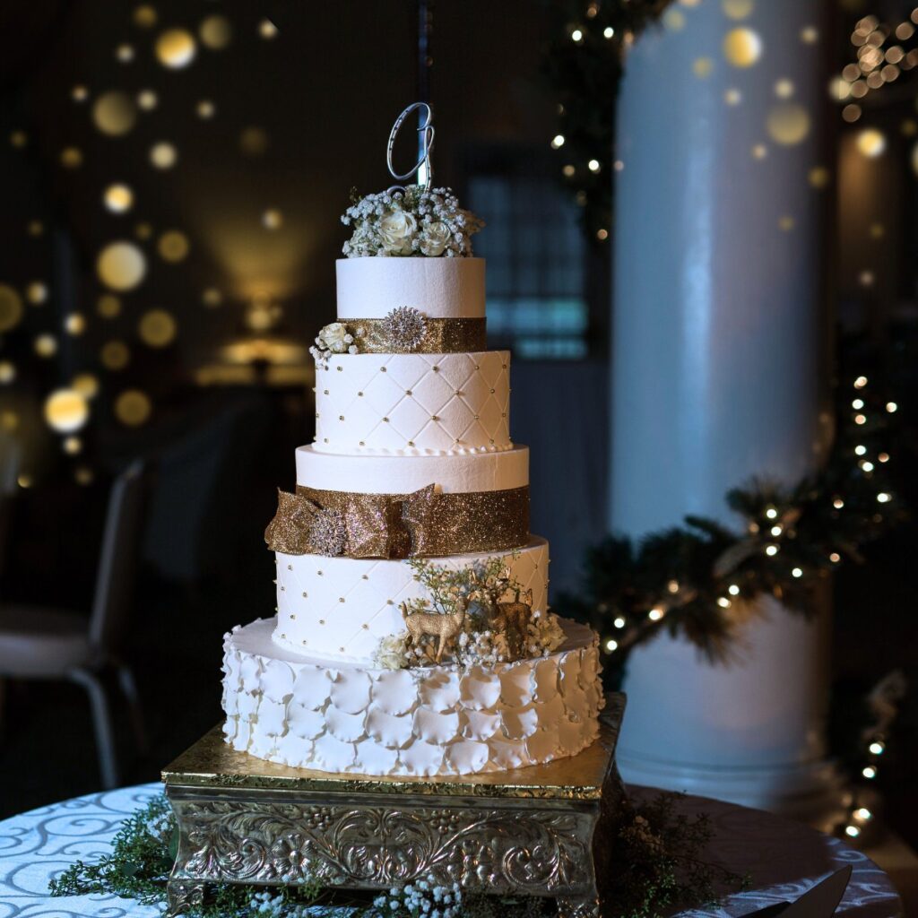 A white winter wedding cake with deer decorations on it.