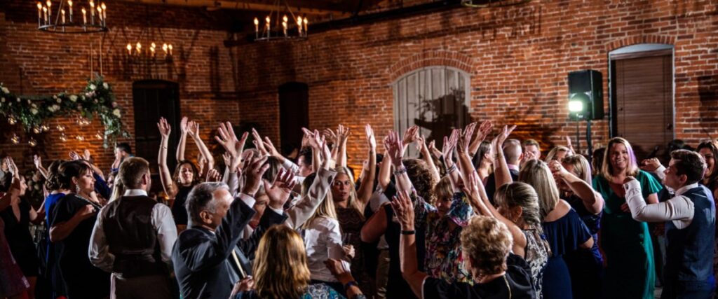 guests dancing and putting their hands in the air at a wedding reception