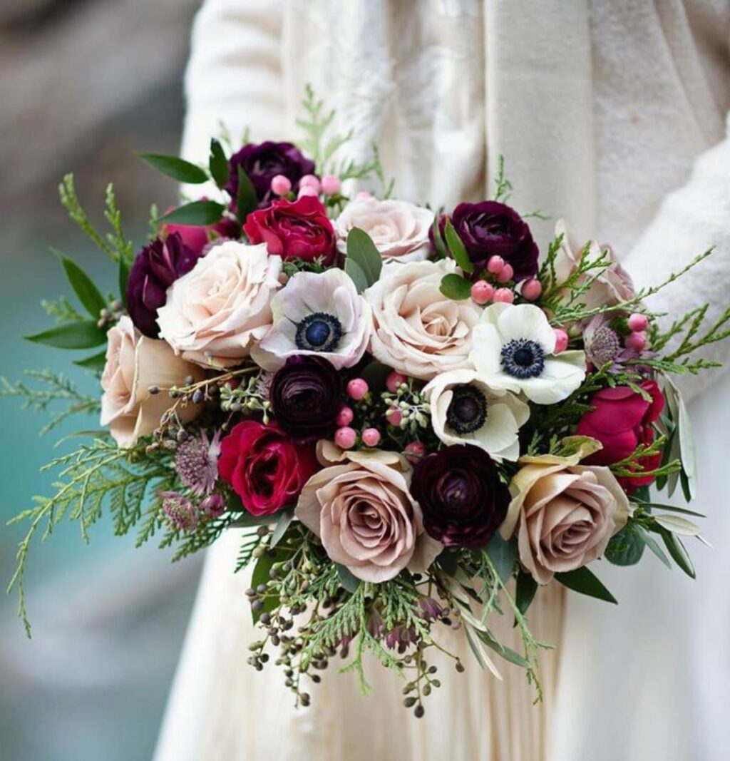 A close up of a winter bride's bouquet with red, white, and pink flowers