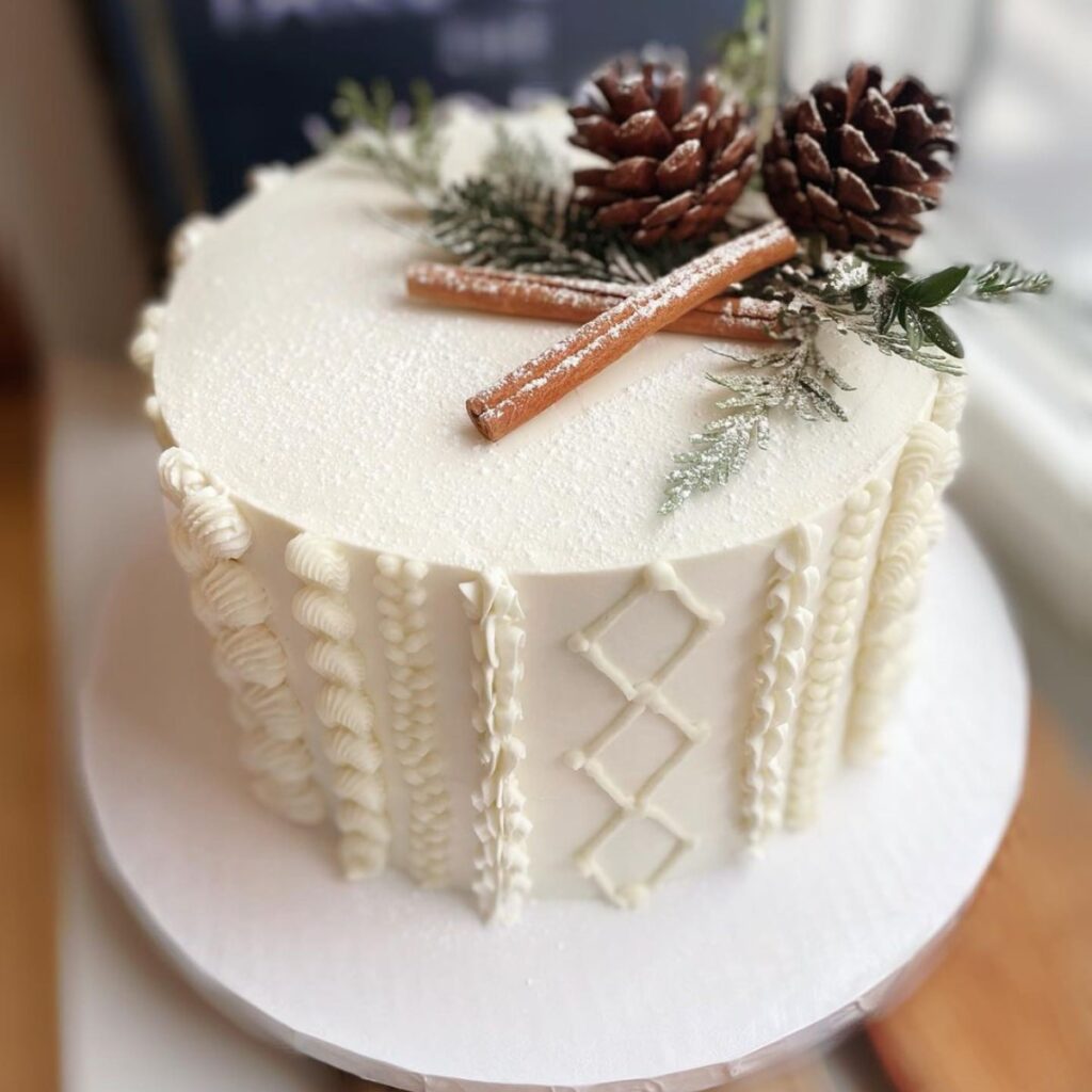 A simple 1-tier winter wedding cake with pine cones and cinnamon sticks on top. This is for the blog post called winter wedding cake ideas.