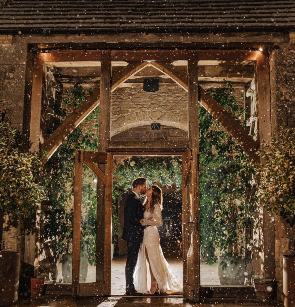 A bride and groom in a doorway while snow is falling outside