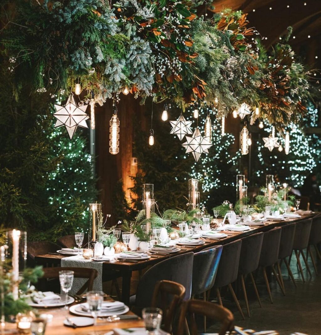 A beautiful of a winter wedding reception. There is lots of evergreen branches and candles.