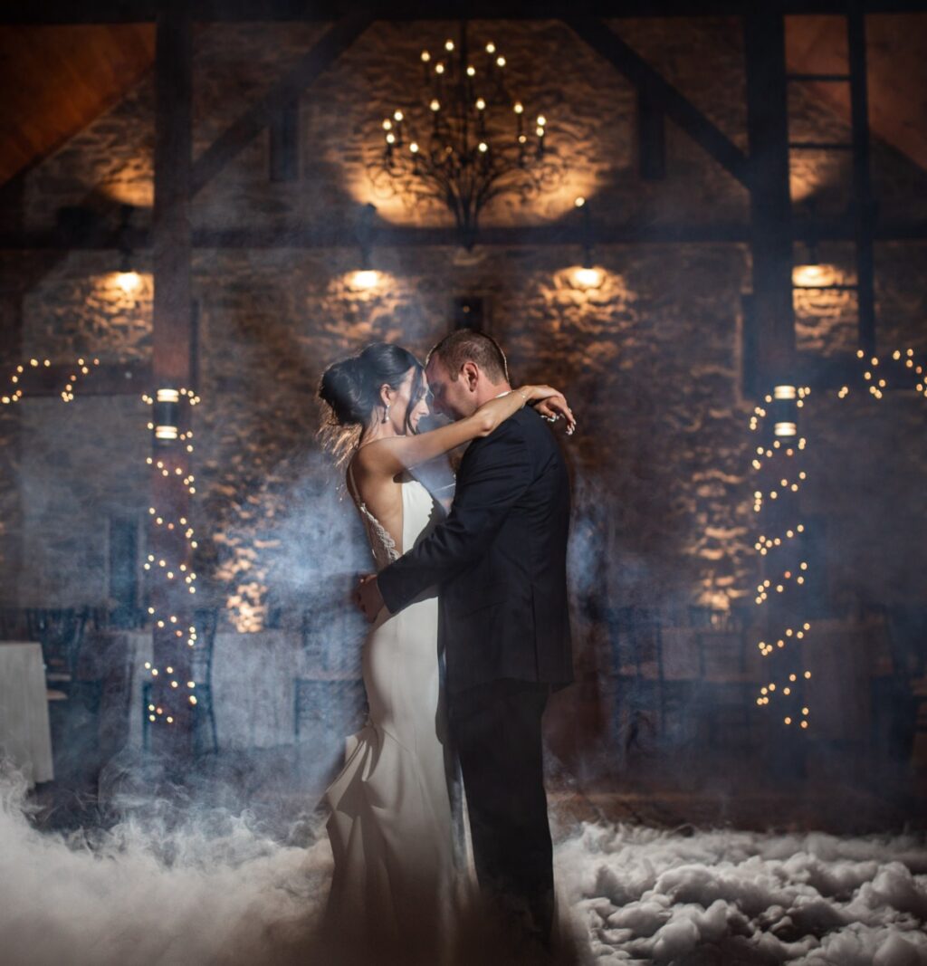 A bride and groom dancing in a cloud of fog at their winter wedding reception