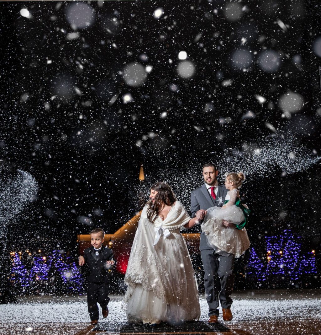 A bride and groom waling into their wedding reception through a bunch of fake snow.
