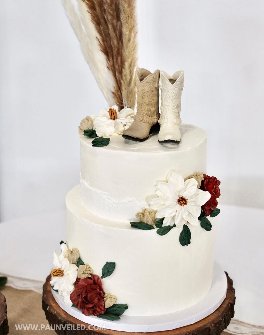 A 2-tier rustic wedding cake with cowboy boots for a cake topper