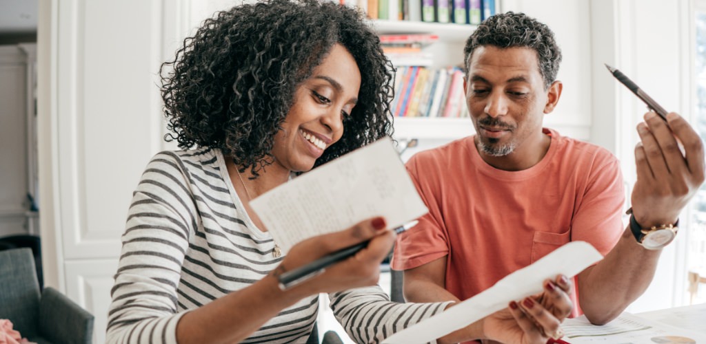 A couple going over their wedding budget at a table in their home