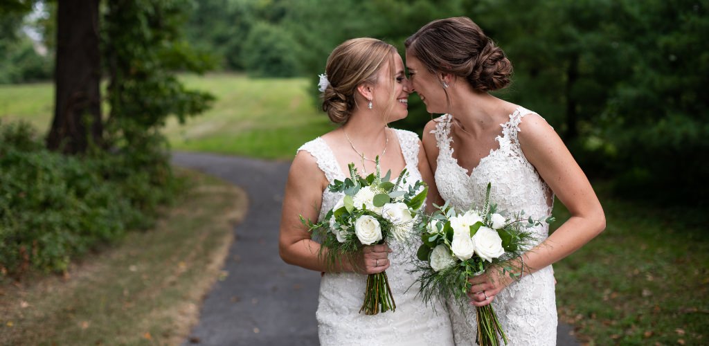 Two brides touching foreheads and posing on their wedding day