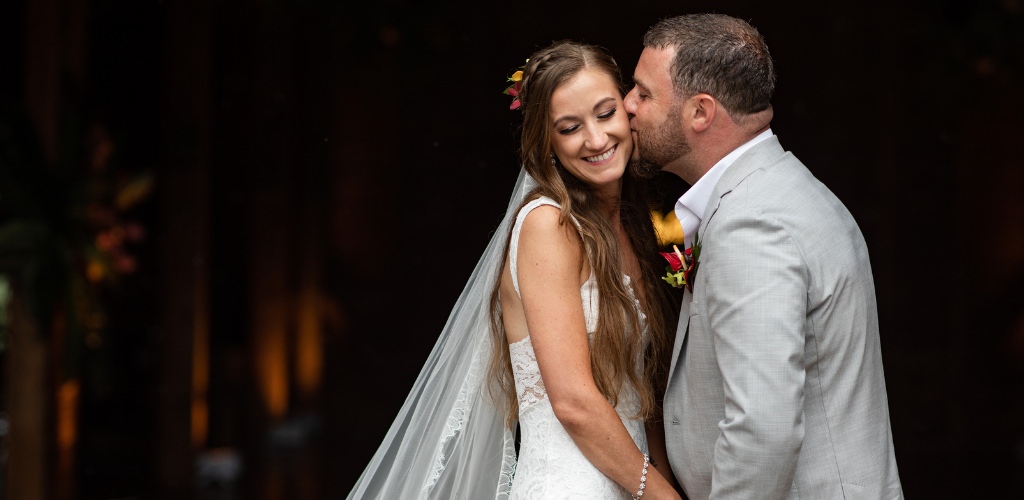 A groom kissing a bride on the cheek