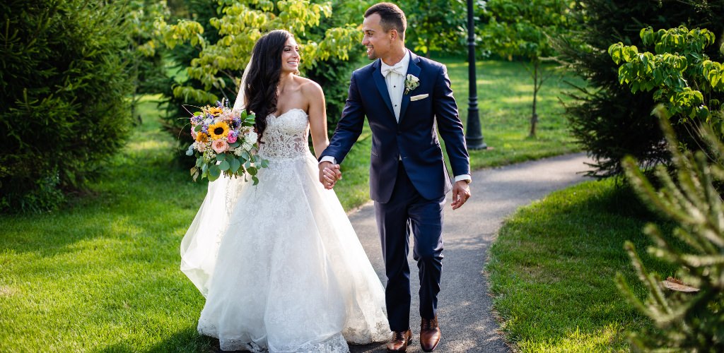 A bride and groom walking together down a path on their wedding day