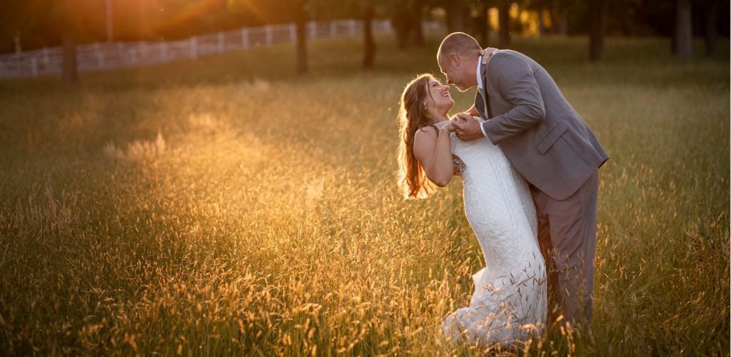 A bride and groom dancing in a field