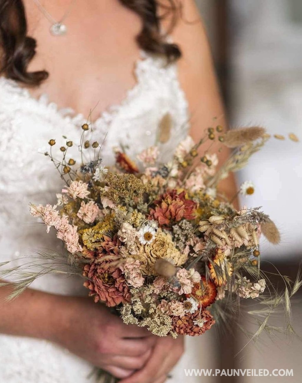 A dried flower wedding bouquet being help by a bride