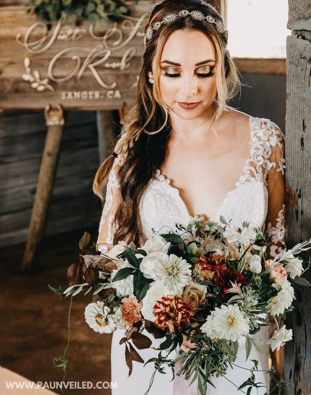 A bride holding a red, burnt orange, and white wedding bouquet