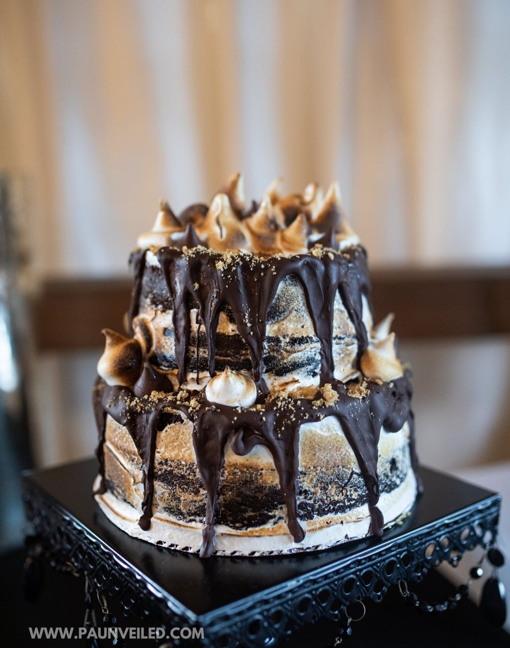 A 2-tier s'mores wedding cake with chocolate drizzle, crushed graham crackers, and toasted marshmallows