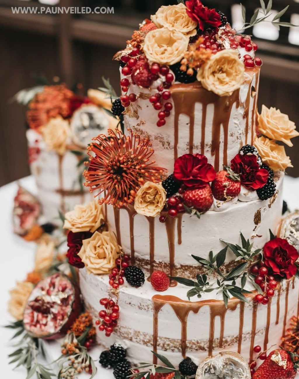 A 3-tier semi-naked wedding cake with fresh flowers and strawberries