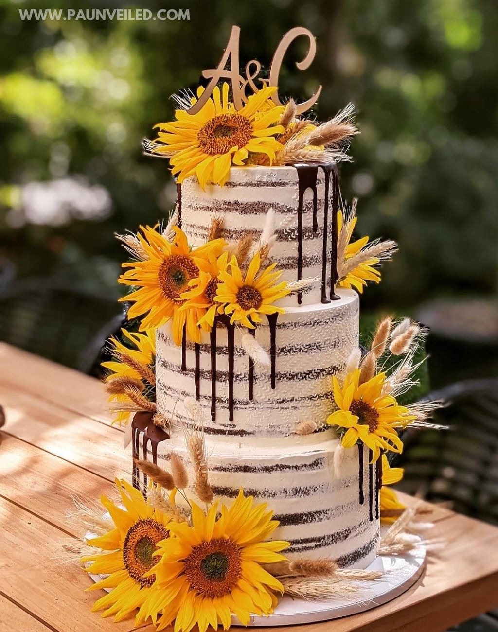 A 3-tier semi-naked rustic wedding cake with chocolate drizzle and big yellow sunflowers